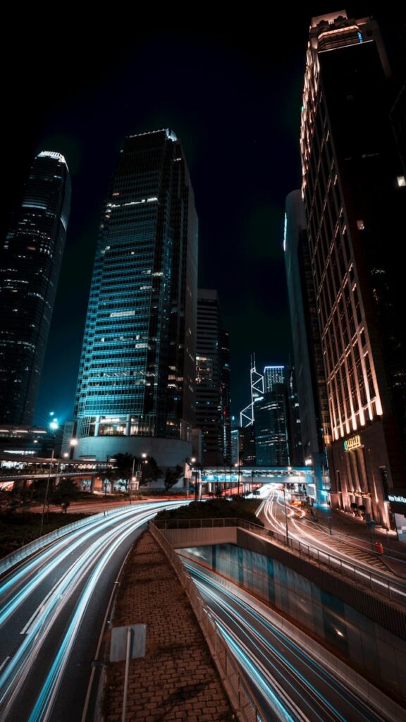 Dramatic night scene of Hong Kong skyscrapers and dynamic light trails on a busy urban road.